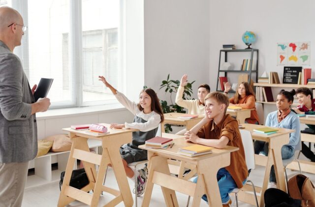 Teacher leading a classroom lesson with students raising hands
